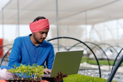 Young indian farmer using laptop at greenhouse - iStock/PRASANNAPiX